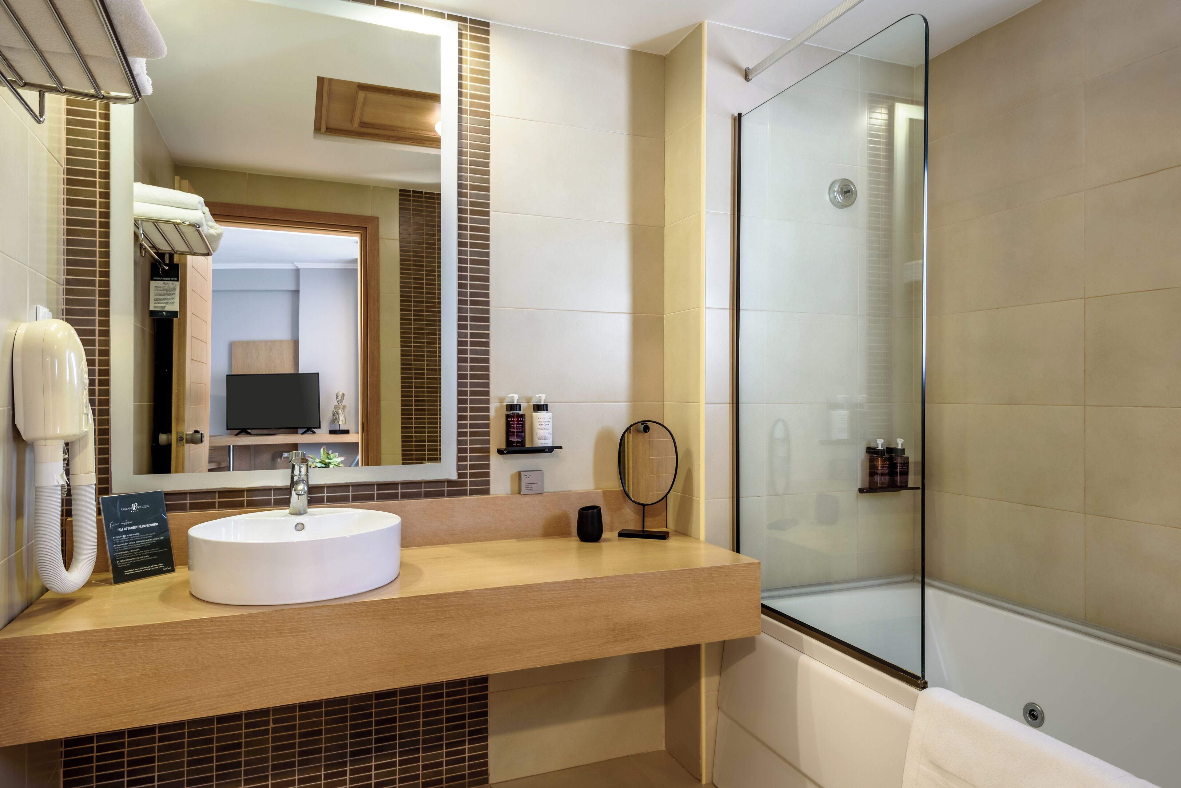 A modern bathroom with a large mirror, a sink, and a glass-enclosed shower.