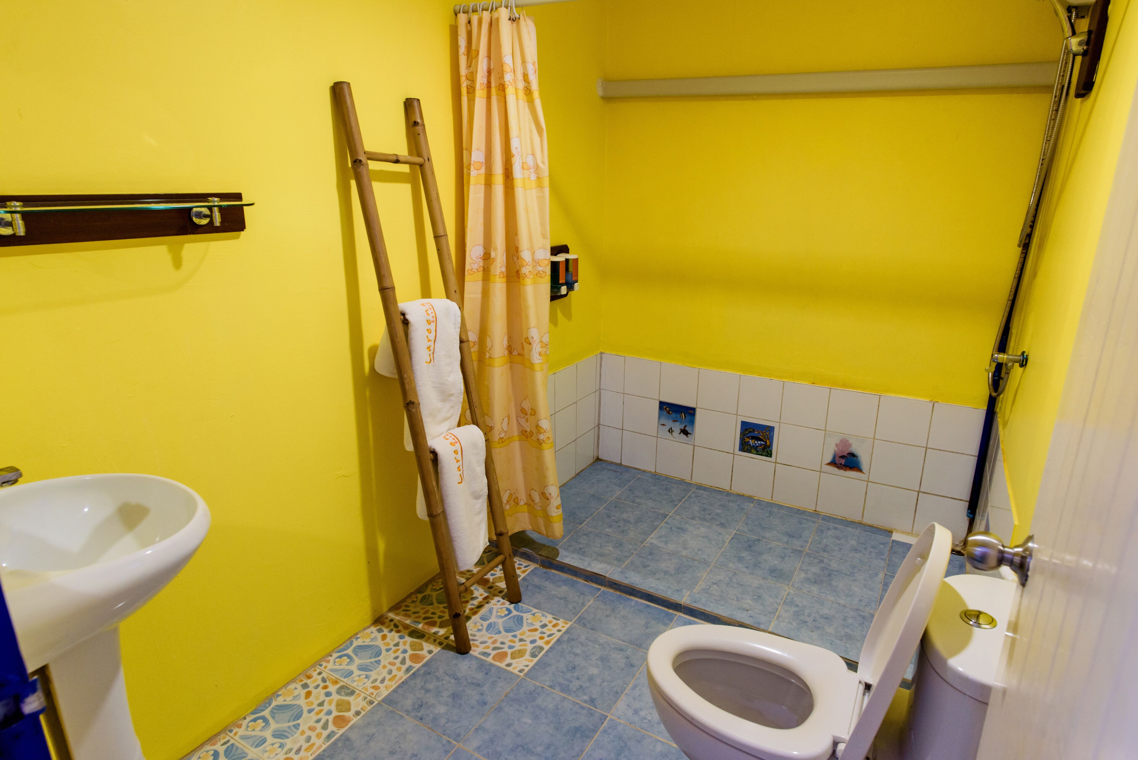 Un bany amb una paret groga, un lavabo blanc, un vàter i una cortina de bany.