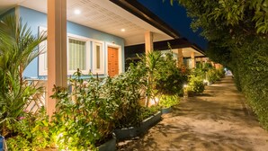 A pathway lined with potted plants leading to a building with a blue facade and a wooden door. - Lareena Resort Koh Larn Pattaya (Koh Lan)