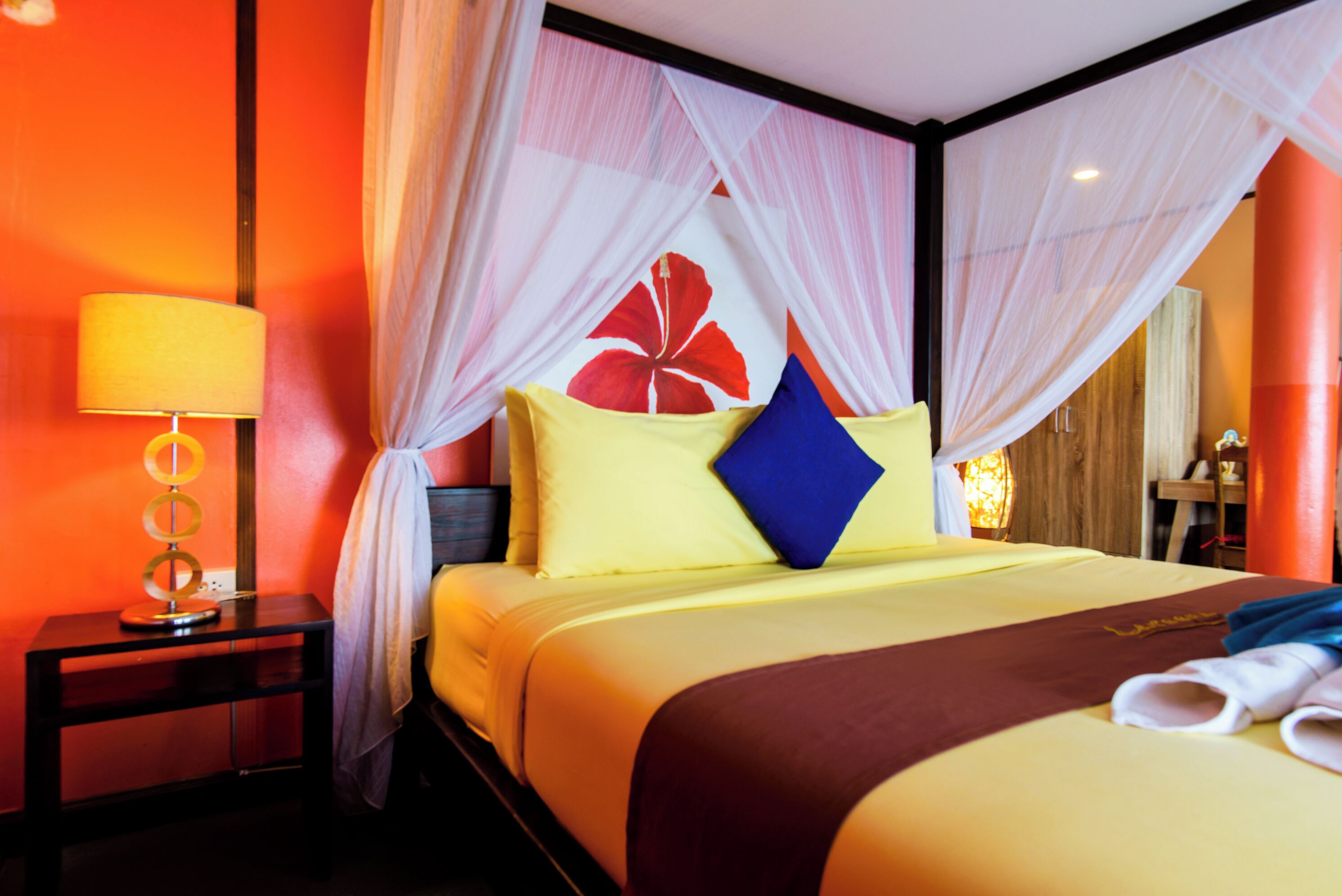 A hotel room with a bed, a nightstand, a lamp, and a mosquito net.
