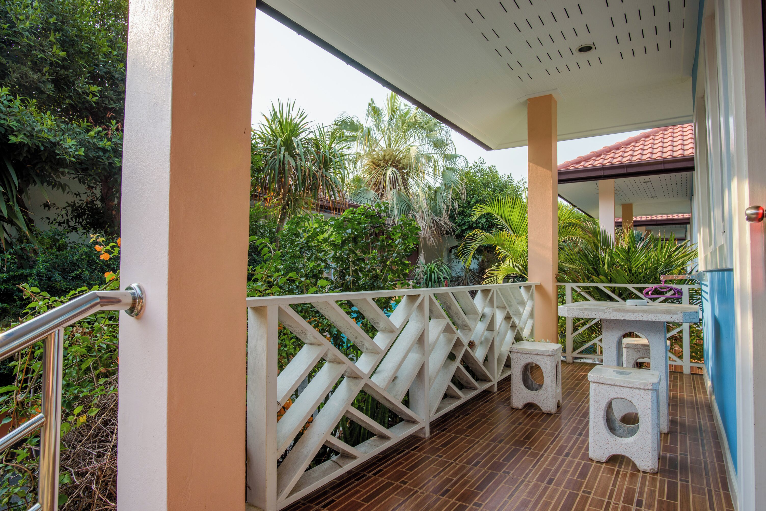 A covered outdoor area with a white railing, a small table, and two stools.