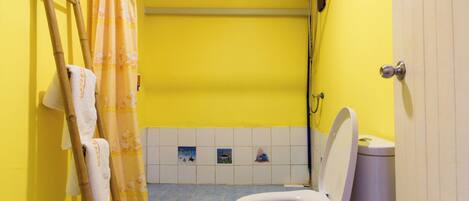 A bathroom with a yellow wall, a white toilet, a shower curtain, and a towel rack.