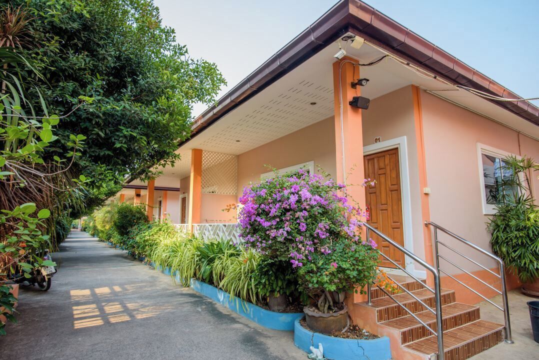 A house with a porch, a staircase, and a variety of plants.