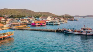 A coastal town with colorful buildings, a pier, and boats docked. - Lareena Resort Koh Larn Pattaya (Koh Lan)