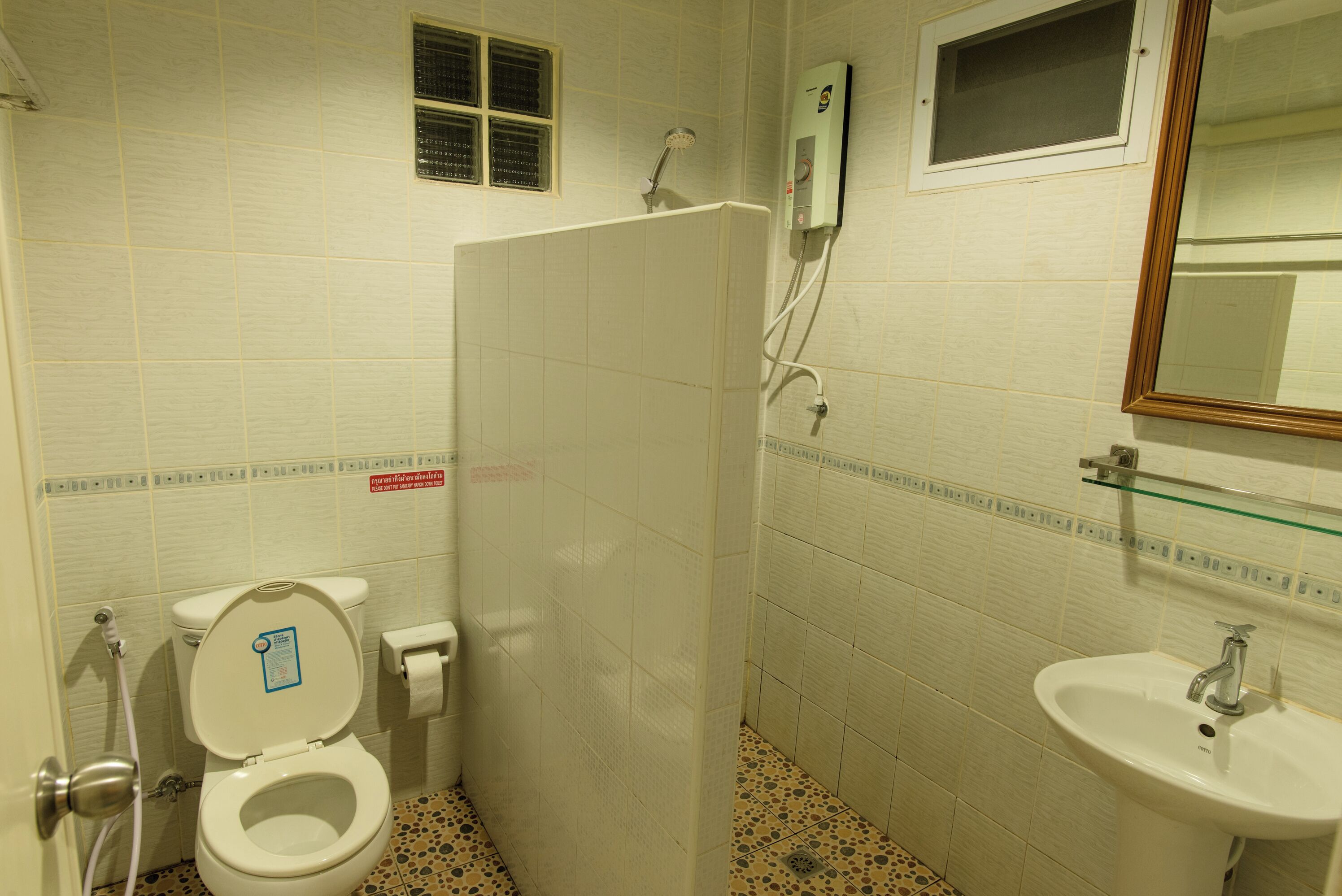A bathroom with a toilet, shower, and sink.