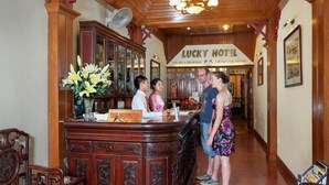 A reception desk with a sign for "Lucky Hotel" and a "Tour Information" sign. - Lucky Hotel (Hanoi)