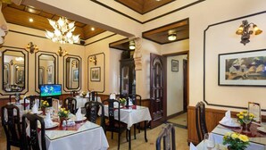 A dining area with tables set for four, each with white tablecloths, chairs, and floral centerpieces. - Lucky Hotel (Hanoi)