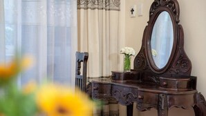 A wooden dresser with a mirror, a chair, and a vase with flowers. - Lucky Hotel (Hanoi)