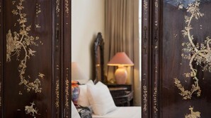 A room with a bed, a lamp, and a mirror with floral designs. - Lucky Hotel (Hanoi)