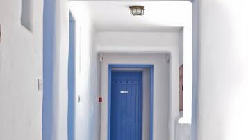 A hallway with a blue door at the end, white walls, and a light fixture above.
