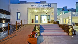 The Naxos Island Hotel entrance with a stone staircase leading up to the doors, a sign above the entrance, and a small garden area with flowers. - Naxos Island Hotel (Naxos)