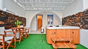 A spa area with a hot tub, wooden seating, and a stone wall. - Naxos Island Hotel (Naxos)