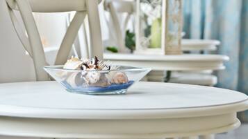 A white table with a bowl of pastries and a white chair.