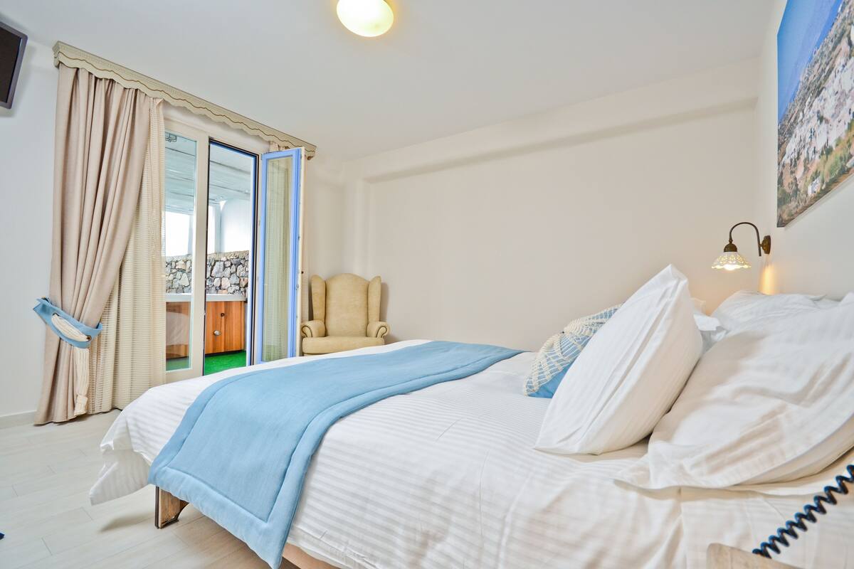 A bedroom with a bed, a chair, a desk, and a painting on the wall.