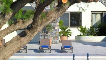 Area piscina con lettini e una pianta in vaso.