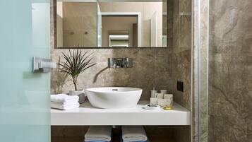 Un baño moderno con un lavamanos blanco, paredes de mármol y un espejo grande.