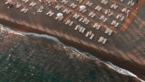 På stranden, sort sand, solsenger og parasoller