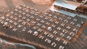 On the beach, black sand, sun loungers, beach umbrellas