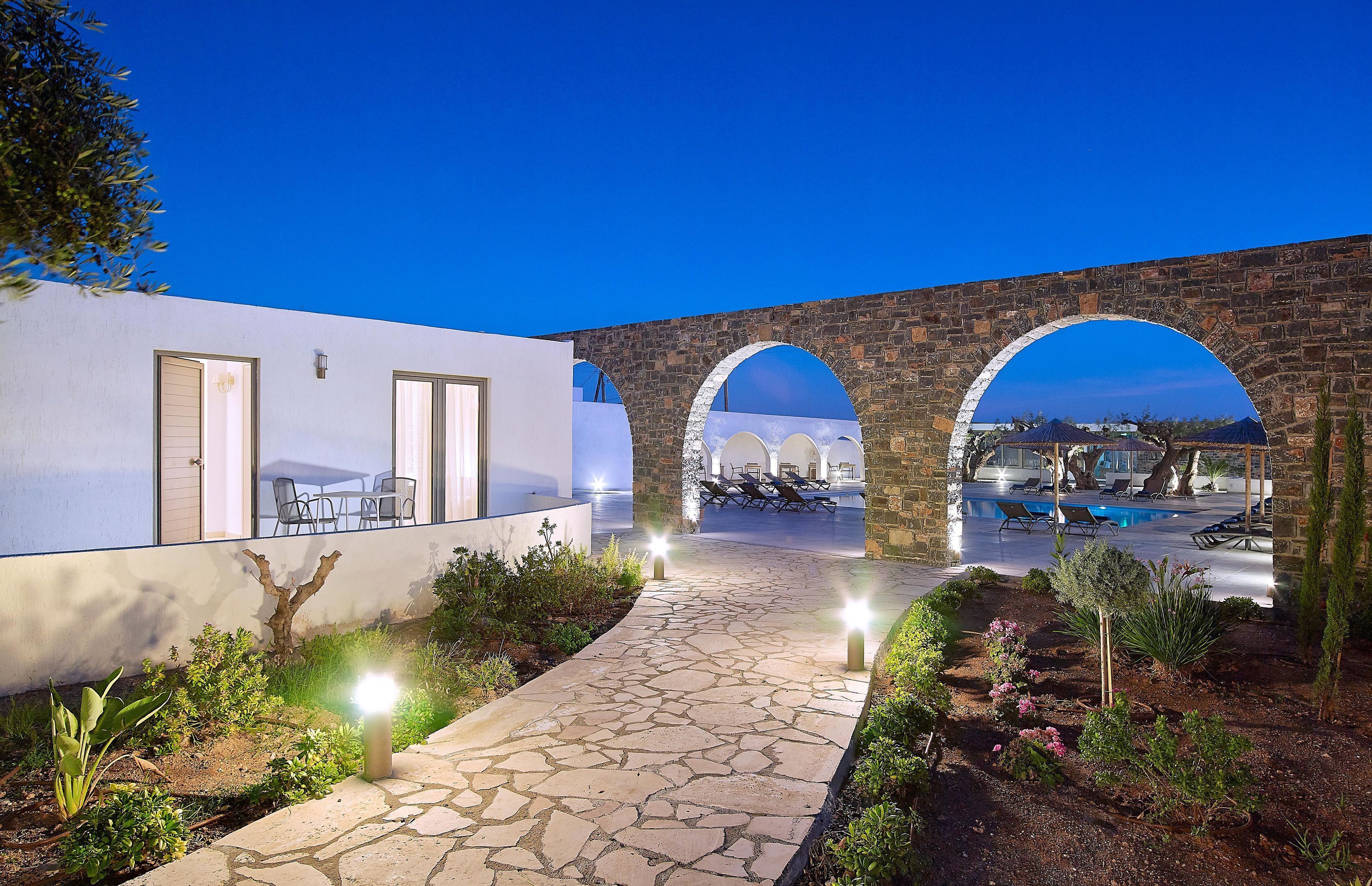 Un edificio moderno con un camino de piedra que lleva a un área de estar al aire libre y una piscina.