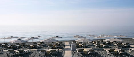 Am Strand, schwarzer Sandstrand, Liegestühle, Sonnenschirme