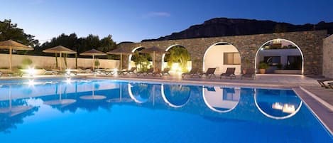 Una piscina al aire libre, sombrillas, sillones reclinables de piscina