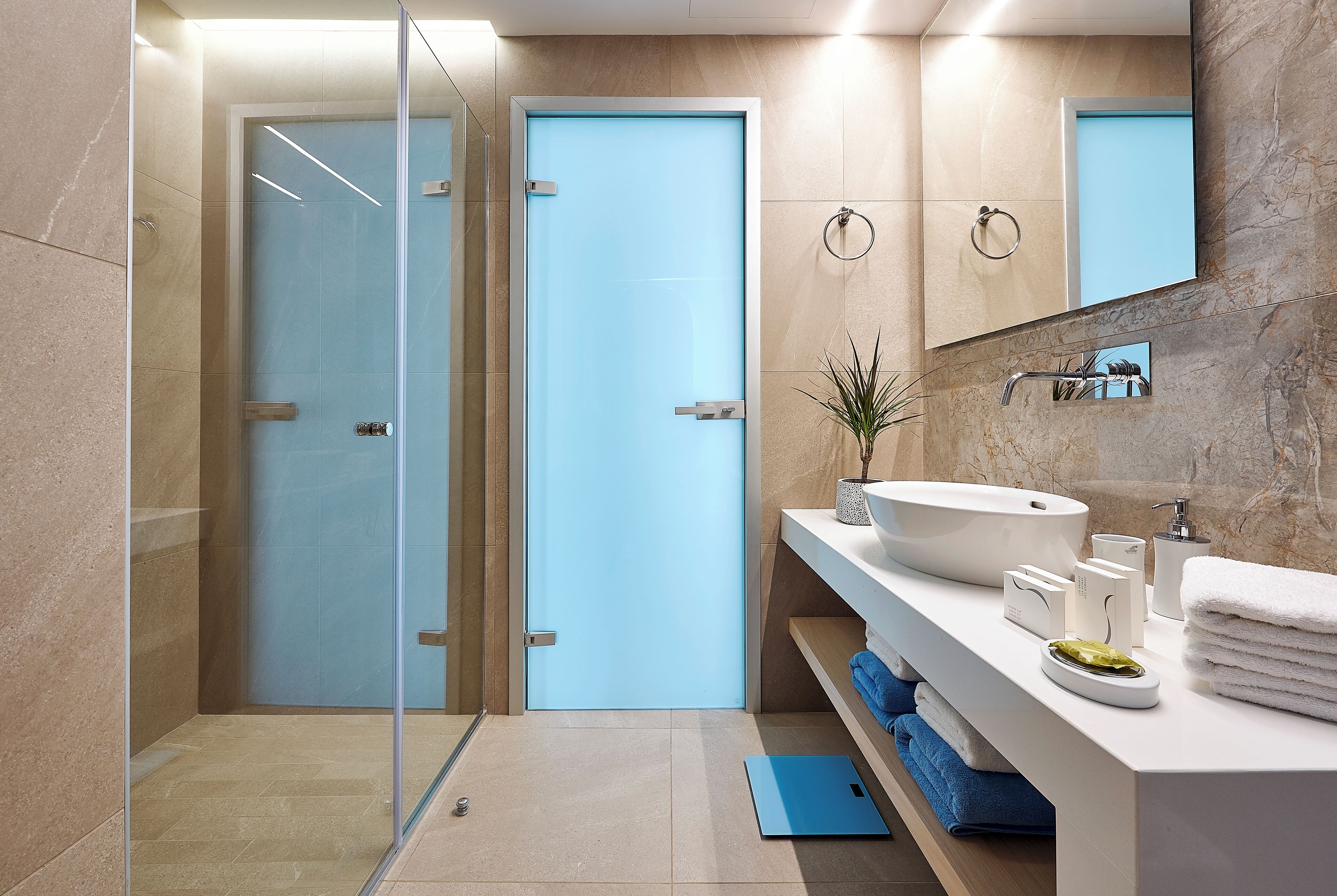 Un baño moderno con cabina de ducha de vidrio, un lavabo blanco y un espejo encima.