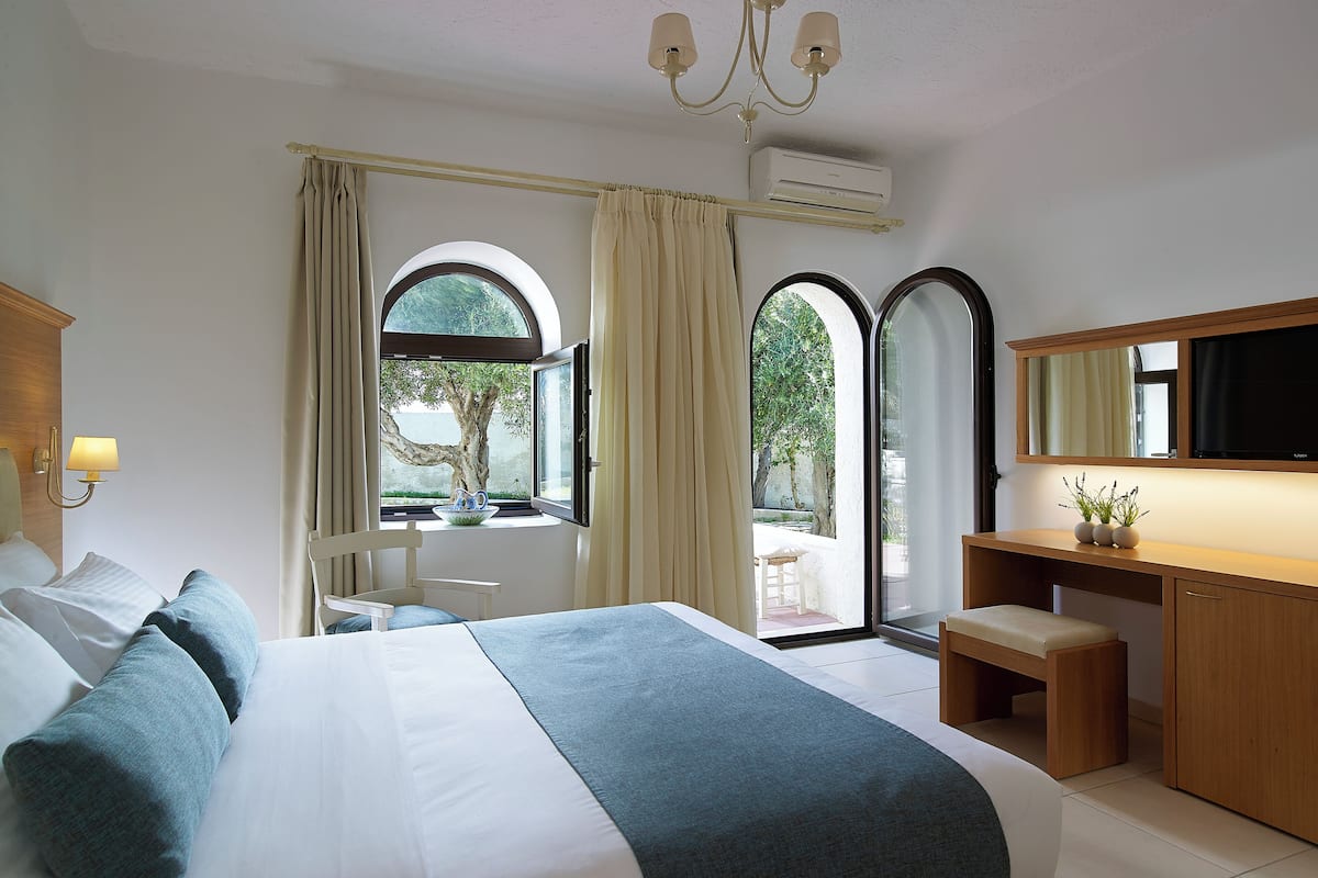 A modern hotel room with a large bed, a desk, a chair, and a TV.