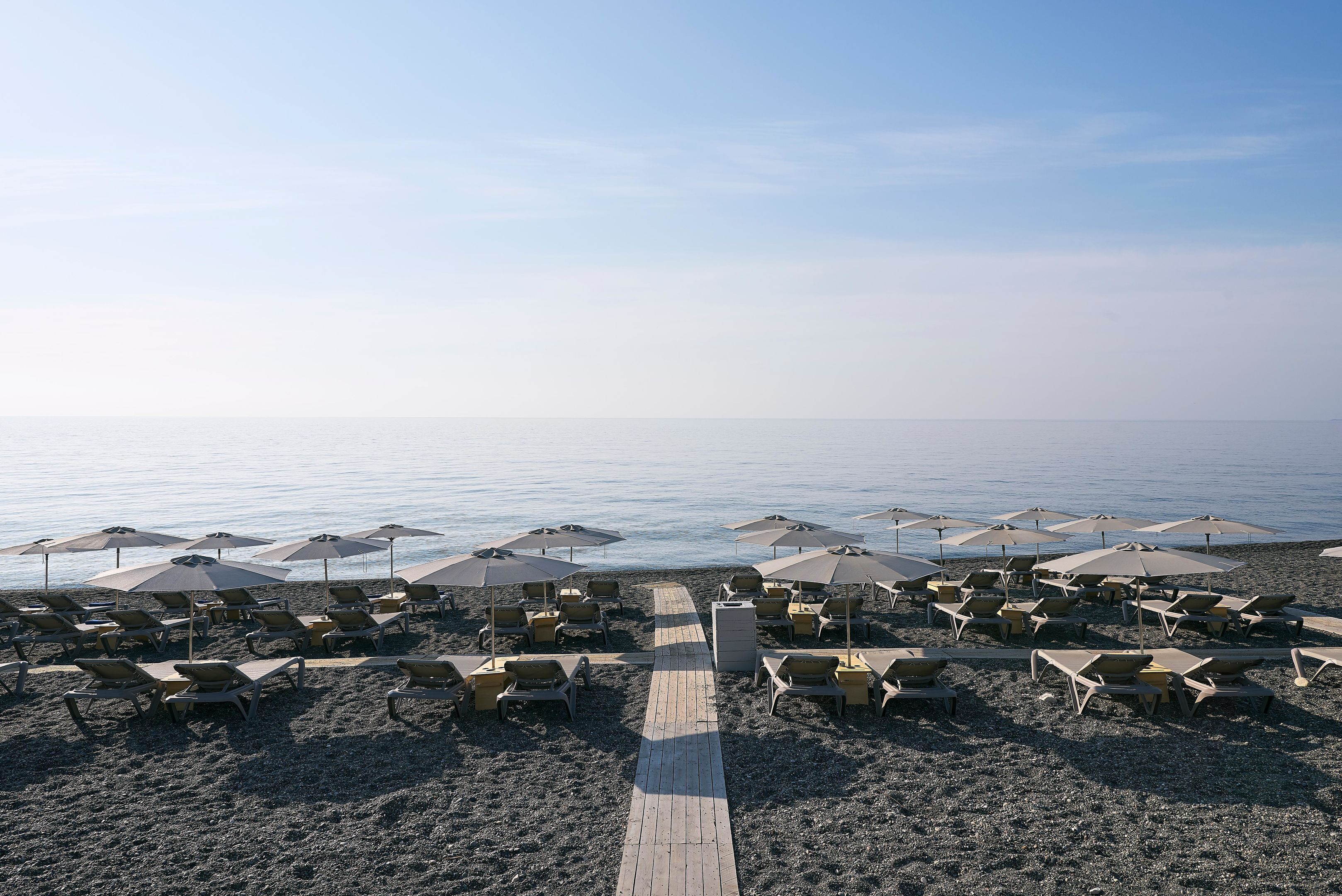 On the beach, black sand, sun-loungers, beach umbrellas