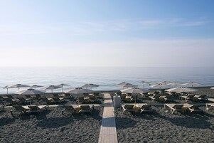 On the beach, black sand, sun loungers, beach umbrellas