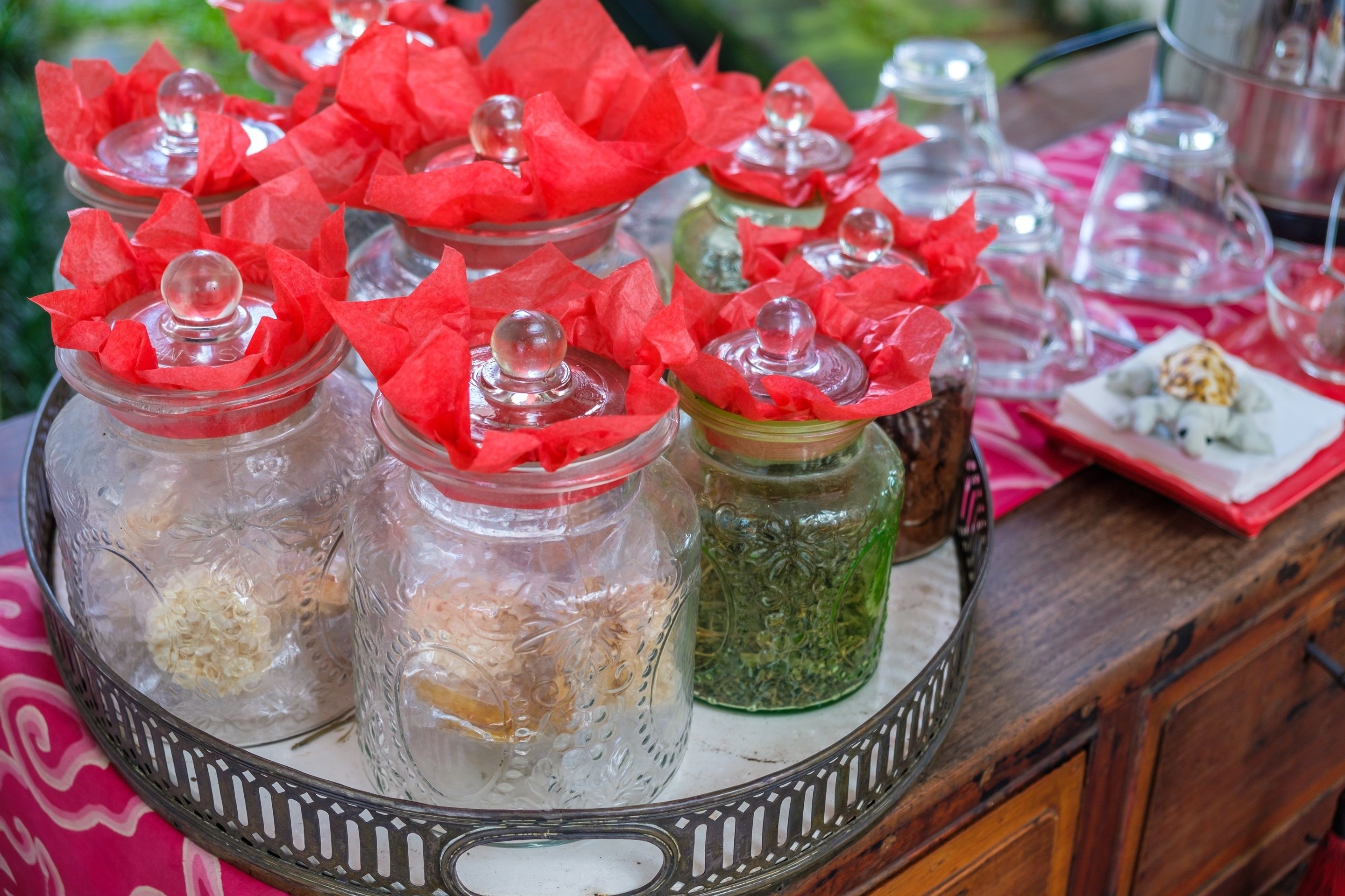 A tray with glass jars containing various food items, each with a red paper bow and a clear lid.