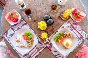 Una escena de desayuno con dos platos de comida, una taza de café y un vaso de jugo sobre una mesa de madera.