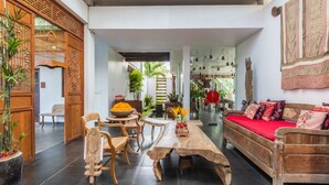 Un salón espacioso con un sofá de madera, una mesa de comedor con sillas y una amplia mesa baja de madera.