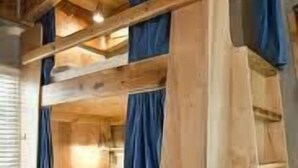 A bunk bed with wooden railings and blue curtains. - The Lounge - Hostel (Koh Samui)