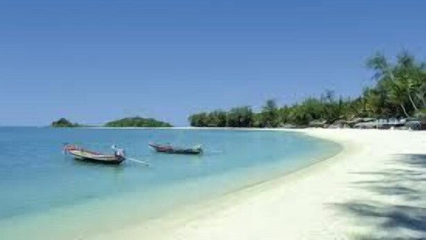 A beach with clear turquoise water, a sandy shore, and two boats anchored near the water's edge. - The Lounge - Hostel (Koh Samui)