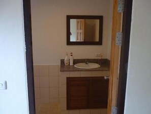 A bathroom with a sink, mirror, and two bottles on the counter. - The Lounge - Hostel (Koh Samui)