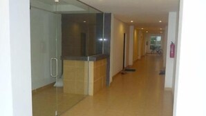 A hallway with a glass partition, a tiled floor, and a fire extinguisher on the wall. - The Lounge - Hostel (Koh Samui)