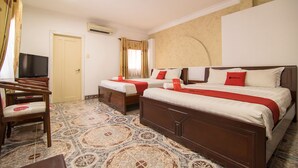 Quarto de hotel com duas camas, televisão e piso estampado.