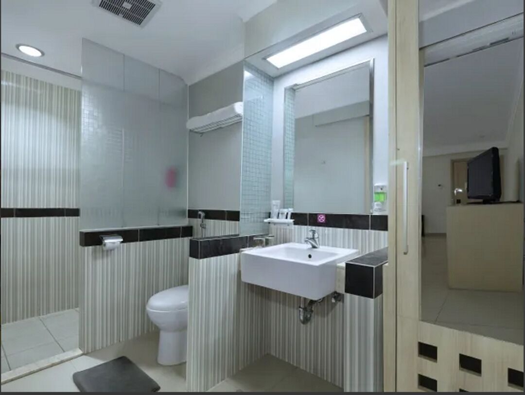 A modern bathroom with a white sink, toilet, and mirror.