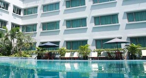 A modern hotel with a pool area, featuring multiple balconies with large windows, sun loungers, and umbrellas. - favehotel Premier Cihampelas (Bandung)