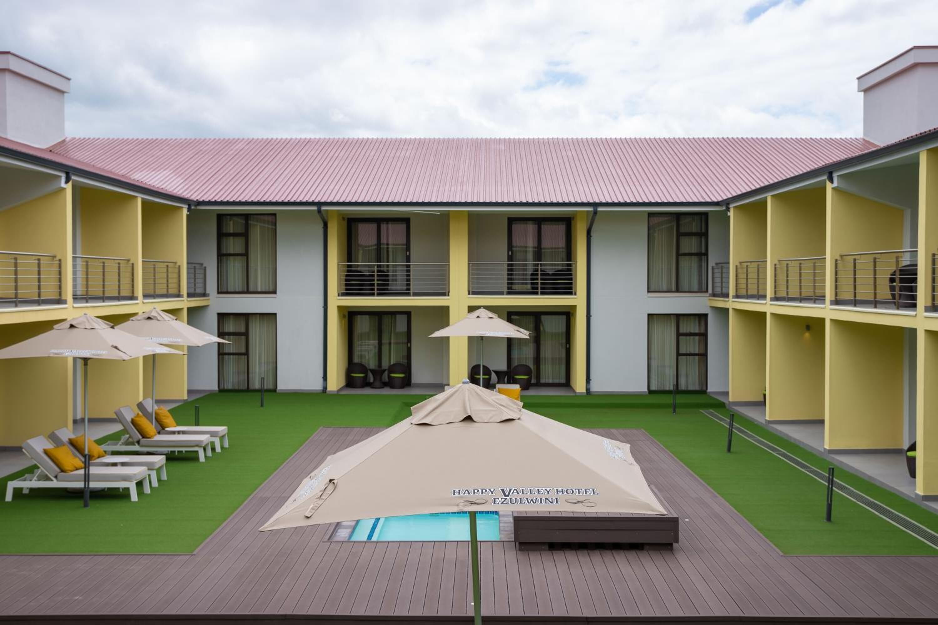 A hotel courtyard with a swimming pool, lounge chairs, and umbrellas.