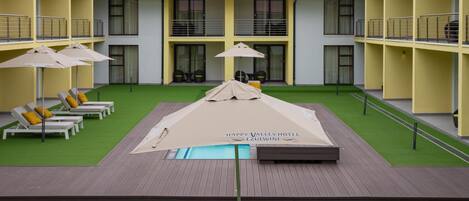 A hotel courtyard with a swimming pool, lounge chairs, and umbrellas.