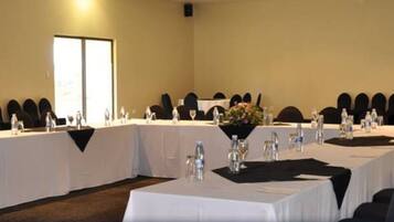 Un salón de conferencias con mesas largas, sillas y botellas de agua.