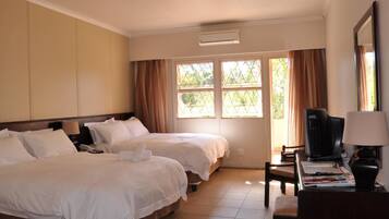 A hotel room with two beds, a desk with a chair, a television, and a window with curtains.