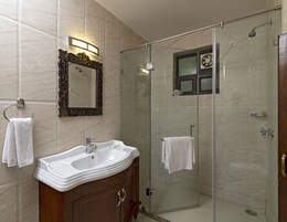 Casa de banho com lavatório, espelho e cabine de duche em vidro.