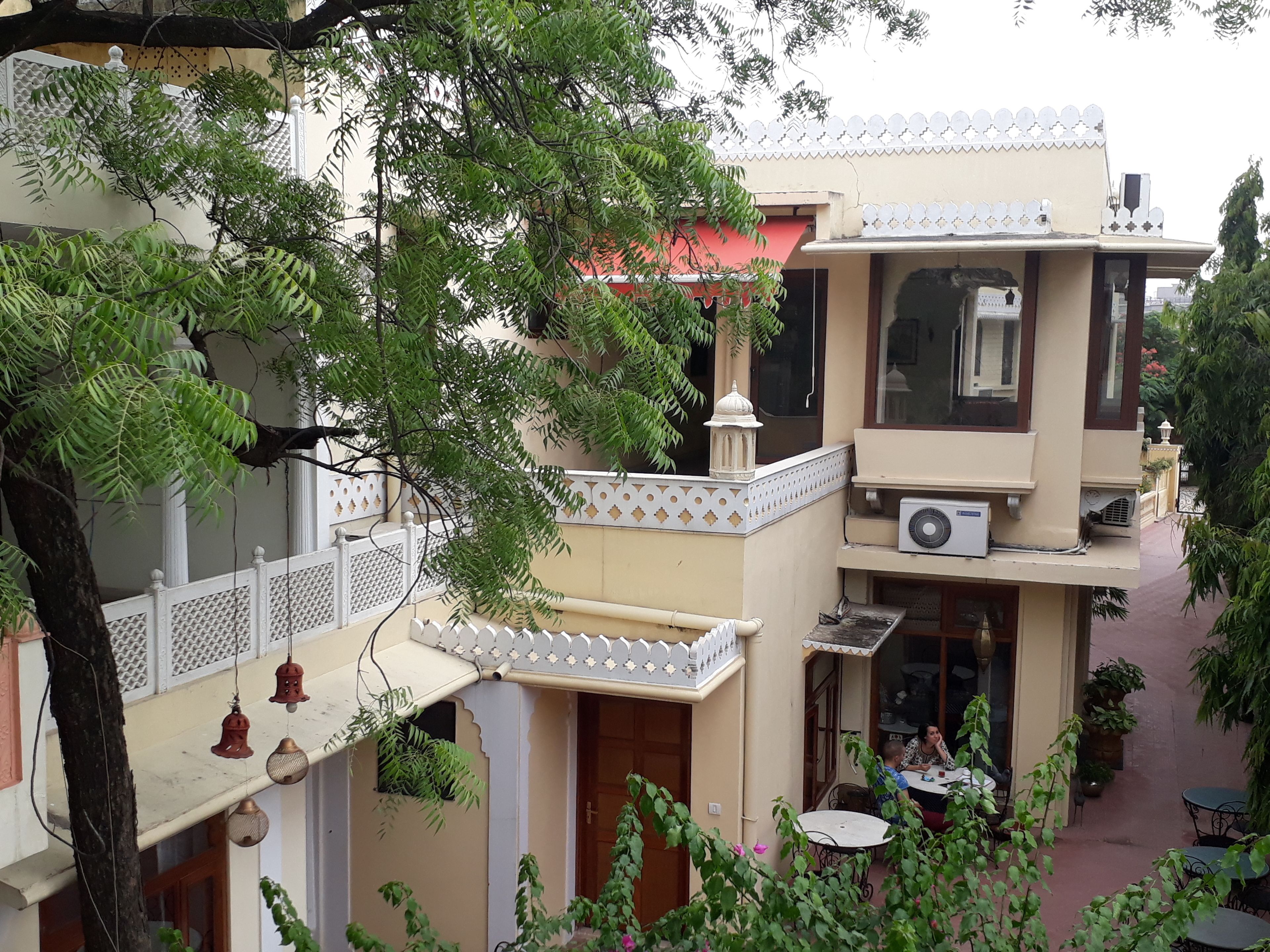 Un edificio de varios pisos con balcones, mesas al aire libre y detalles decorativos.