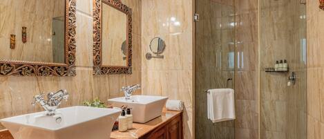 A bathroom with two sinks, a large mirror, and a glass-enclosed shower.