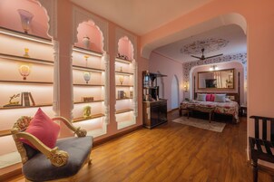 A room with a bed, a chair, a coffee table, and shelves with decorative items.