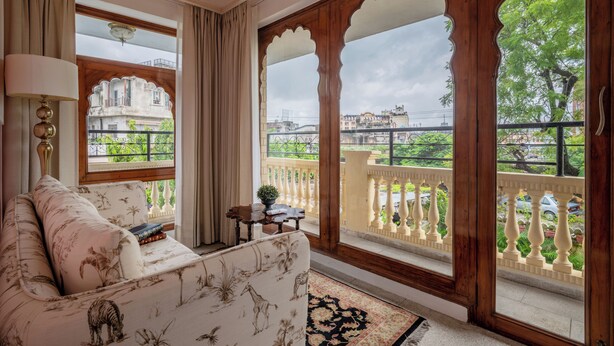 Una habitación con sofá, lámpara y vistas a un balcón con barandillas y vegetación.