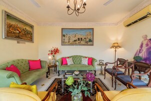 A living room with a green sofa, a wooden coffee table, and a painting of a fort.
