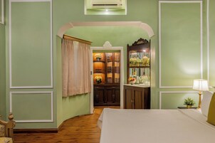 Un dormitorio con cama, mesita de noche, lámpara y vistas a un pasillo que lleva a un baño.
